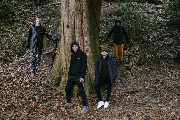 A group of young people stood by a tree.